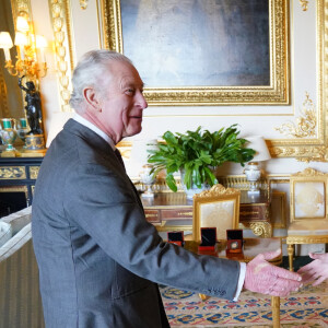 Le roi Charles III d'Angleterre, se voit présenter les pièces à son effigie, frappées à l'occasion de son prochain couronnement, au château de Windsor, le 13 avril 2023. La PDG de Royal Mint, Anne Jessopp et la directrice, Rebecca Morgan, montrent au souverain les pièces de 50 pence et de 5 livres qui seront mises en circulation ce mois-ci, avant l'événement du 6 mai 2023. 