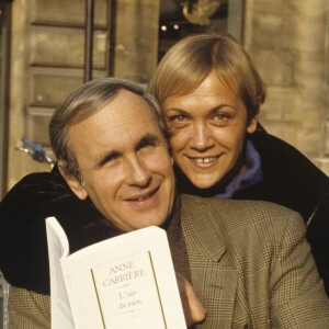 Archives - En France, à Paris, portrait d'Anne CARRIERE et Patrice LAFFONT assis sur un banc, tenant le livre de sa soeur Anne CARRIERE, "L'AIR DE RIEN" ed JULLIARD, celle-ci placée derrière lui, le tenant par le cou. . © Michel Marizy via Bestimage