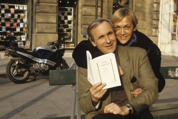 Archives - En France, à Paris, portrait d'Anne CARRIERE et Patrice LAFFONT assis sur un banc, tenant le livre de sa soeur Anne CARRIERE, "L'AIR DE RIEN" ed JULLIARD, celle-ci placée derrière lui, le tenant par le cou. . © Michel Marizy via Bestimage