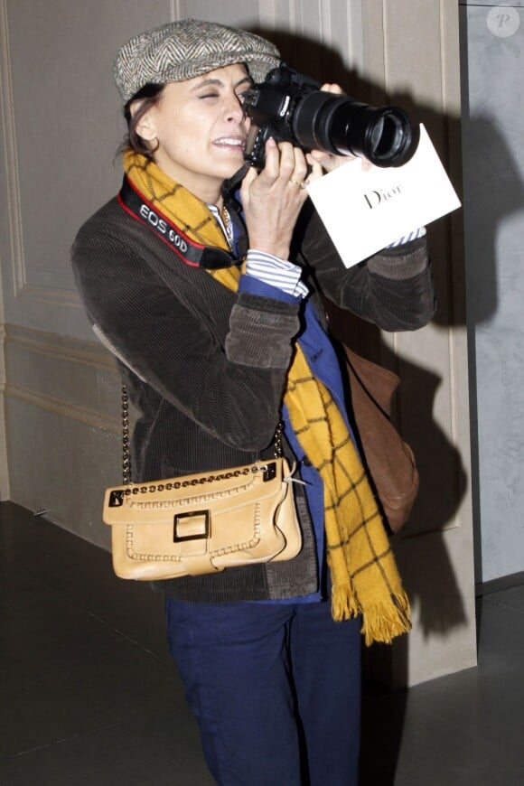 Inès de la Fressange, stylée en reporter photographe, se la joue Terry Richardson lors du défilé Christian Dior haute couture à Paris, le 23 janvier 2012.