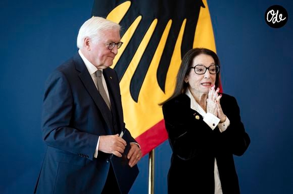 Enfant, elle a connu l'occupation allemande à Athènes pendant la Seconde Guerre mondiale.

Nana Mouskouri reçoit la Croix Fédérale du Mérite, des mains Frank-Walter Steinmeier (Président fédéral de l'Allemagne) au siège officiel du Spreebogen, à Berlin, le 5 octobre 2026. Action Press / Bestimage