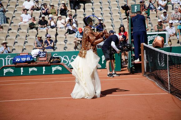 Elle est arrivée sur le court vêtue de son ensemble Nike beige à sequins, agrémenté cette fois-ci d'une longue traîne blanche.

Naomi Osaka arrive avec une traine blanche pour son second tour aux internationaux de France de Tennis de Roland Garros 2026, à Paris, France, le 28 mai 2026. © Imago/PsnewZ/Bestimage