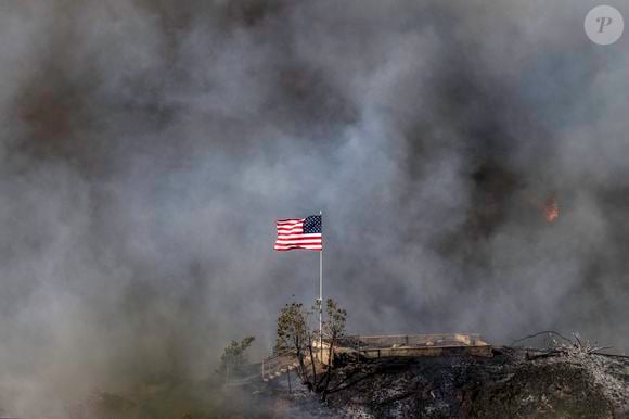 Pacific Palisades - 11 janvier 2025, Los Angeles, Californie, USA : Un drapeau américain flotte au-dessus d'une section de Mandeville Canyon détruite par l'incendie de Palisades. (Crédit photo : © Mark Edward Harris/ZUMA Press Wire)