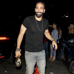 Exclusif - Adil Rami, défenseur de l’équipe de France et compagnon de Pamela Anderson arrive au club Warwick à Los Angeles pour célébrer la victoire des bleus, une réplique du trophée de la coupe du monde en main. Le 18 juillet 2018. Backgrid USA / Bestimage