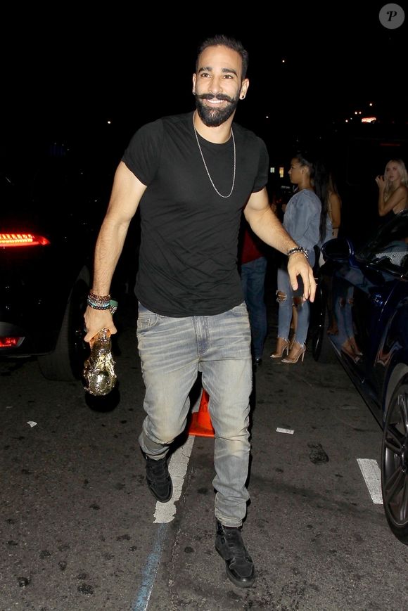 Exclusif - Adil Rami, défenseur de l’équipe de France et compagnon de Pamela Anderson arrive au club Warwick à Los Angeles pour célébrer la victoire des bleus, une réplique du trophée de la coupe du monde en main. Le 18 juillet 2018. Backgrid USA / Bestimage