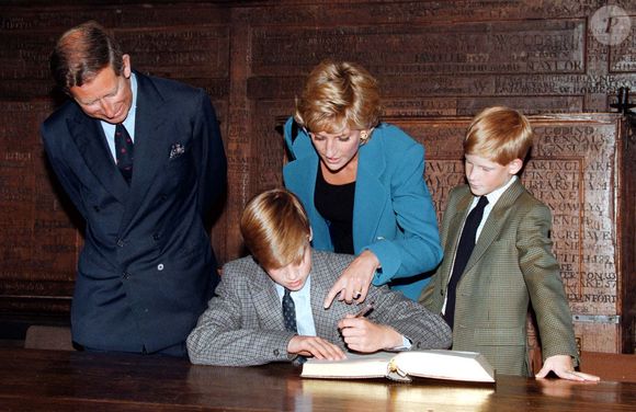 Le prince William signant le traditionnel livre d'entrée sous le regard de ses parents, le Prince et la Princesse de Galles, et de son jeune frère, le Prince Harry, à Eton College le 6 septembre 1995. PA Wire