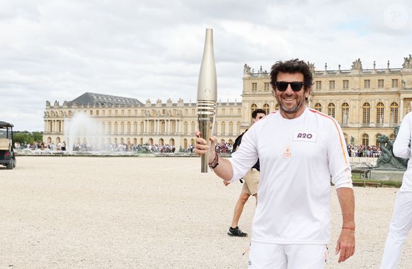 Le chanteur et acteur Patrick Bruel porteur de la flamme olympique des Jeux Olympiques de Paris 2024 (JO) au château de Versailles dans les Yvelines, France, le 23 juillet 2024. © Dominique Jacovides/Bestimage