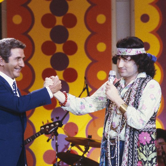 Photo prise dans les années 80 du présentateur de télévision français Michel Drucker, habillé comme un hippie, avec le chanteur Gilbert Becaud sur le plateau des Champs Elysées. Photo by Pascal Baril/ABACAPRESS.COM