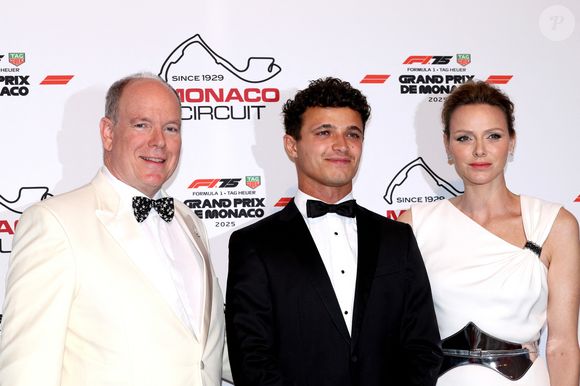 Son époux avait lui aussi choisi du blanc : le prince portait une veste de smoking de cette couleur, ainsi qu'un pantalon noir. Ensemble, ils ont posé avec élégance aux côtés du champion du jour, Lando Norris.

Lando Norris avec le prince Albert II de Monaco, la princesse Charlene de Monaco lors de la soirée de gala du Grand Prix de Formule 1 de Monaco à la salle des étoiles au Monte-Carlo Sporting à Monaco le 25 mai 2025. © Claudia Albuquerque / Bestimage