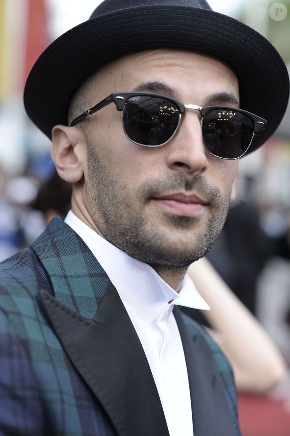 S'il n'est pas allé aussi loin que les Daft Punk, en optant pour un casque, le photographe a choisi des chapeaux noirs et ses lunettes de soleil rondes.

Le photographe JR - Arrivées à la montée des marches du film "The BFG" ("Le BGG Le Bon Gros Géant") lors du 69ème Festival International du Film de Cannes. Le 14 mai 2016.