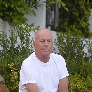 Exclusif - Bruce Willis est assis pieds nus sur un rocher et regarde passer les voitures sur Sunset Boulevard à Los Angeles, le 22 septembre 2019. Il porte un jean et un t-shirt blanc.