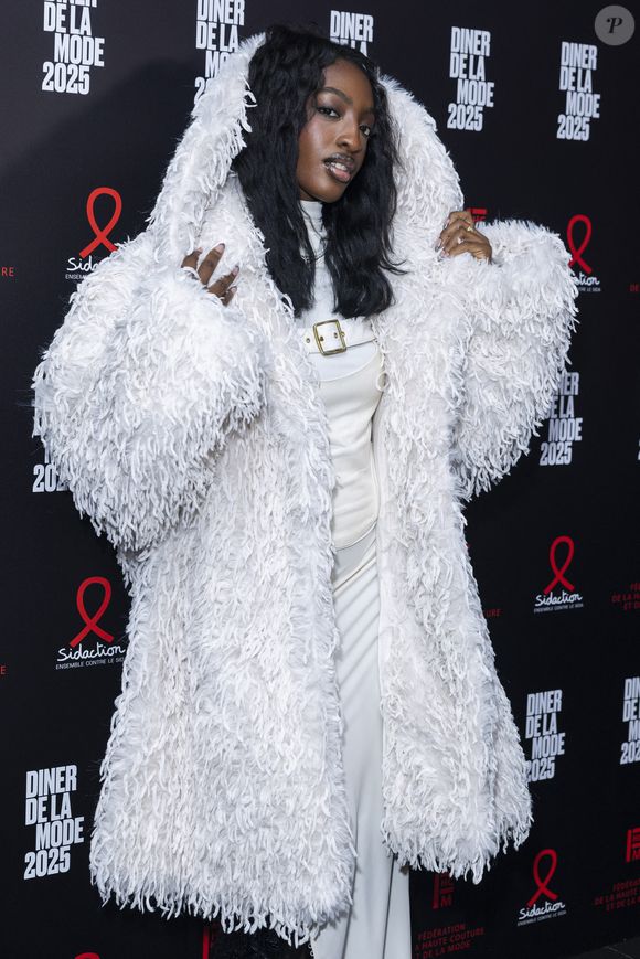 Une tenue composée d'une longue robe fluide surmontée d'un corset en cuir et d'un manteau XXL à capuche
Ebony Cham au photocall du 22ème dîner de la mode pour le Sidaction à Paris le 30 janvier 2025.
© Olivier Borde / Bestimage
