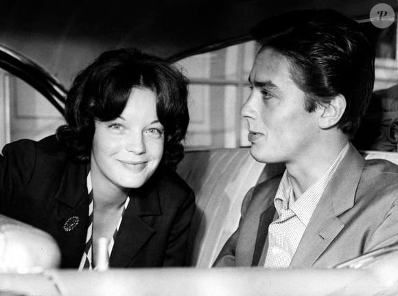 13 juillet 1959 - Munich, Bavière, Allemagne - C’est lors du tournage de Christine que Romy Schneider est tombée amoureuse de l’acteur français Alain Delon, qui partageait l’affiche du film. Elle quitta brusquement l’Allemagne pour le rejoindre à Paris, provoquant un scandale national. Schneider s’est fiancée à Delon en 1959. Ce fut un moment charnière dans sa vie personnelle et professionnelle. Le magnétique Alain Delon faisait partie des acteurs français les plus en vue de l’après-guerre ; d’une beauté exotique, il est passé des rumeurs et scandales hors écran pour devenir un talent singulièrement énigmatique et fascinant. Photographié dans une voiture devant l’aéroport de Munich-Riem. (Crédit image : © KEYSTONE Pictures USA)