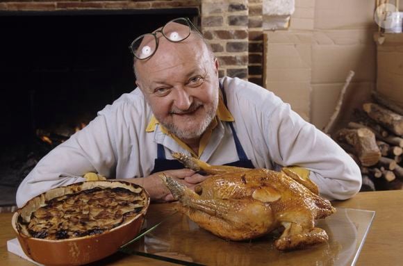 En France, chez lui, portrait de Jean-Pierre Coffe, dans sa maison en Eure-et-Loire, assis derrière une table devant une cheminée allumée, le 05/12/1995. Crédit Alain Canu / Bestimage