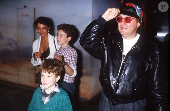 France, 29 juin 1985. Coluche et son amie à la sortie de l’émission "Champs-Élysées" avec ses fils Romain et Marius. (Photo : AGENCE / BESTIMAGE)
