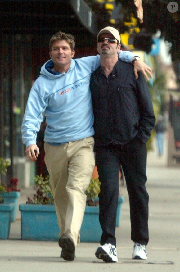 En effet, George Michael avait fait le choix de ne rien léguer de sa fortune à son ex petit ami Kenny Goss, avec qui il a pourtant passé 15 ans de sa vie...

George Michael et son ex petit ami de longue date Kenny Goss se promènent bras dessus bras dessous à Hollywood, Californie. Le 16 janvier 2002. Crédit Pacific Coast News/Abaca