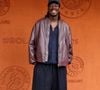 Mory Sacko, fidèle à son style décontracté mais pointu, a pris la pose dans une superbe veste bomber bordeaux superposée sur un cardigan sombre et complétant son look avec une casquette bleu marine. 

Mory Sacko au village lors des Internationaux de France de Tennis de Roland Garros le 3 juin 2026

Jacovides / Moreau / Bestimage