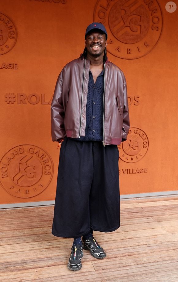 Mory Sacko, fidèle à son style décontracté mais pointu, a pris la pose dans une superbe veste bomber bordeaux superposée sur un cardigan sombre et complétant son look avec une casquette bleu marine. 

Mory Sacko au village lors des Internationaux de France de Tennis de Roland Garros le 3 juin 2026

Jacovides / Moreau / Bestimage