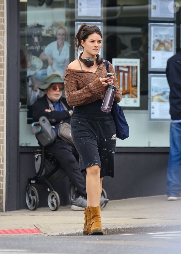 New York, NY - EXCLUSIF - Suri Noelle Cruise porte un cardigan court en maille marron avec un short ample noir à taches de peinture et des bottes en daim beige. Elle porte un sac bleu marine, un téléphone et une bouteille d'eau à la main.

Backgrid USA / Bestimage