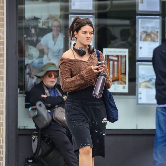 New York, NY - EXCLUSIF - Suri Noelle Cruise porte un cardigan court en maille marron avec un short ample noir à taches de peinture et des bottes en daim beige. Elle porte un sac bleu marine, un téléphone et une bouteille d'eau à la main.

Backgrid USA / Bestimage