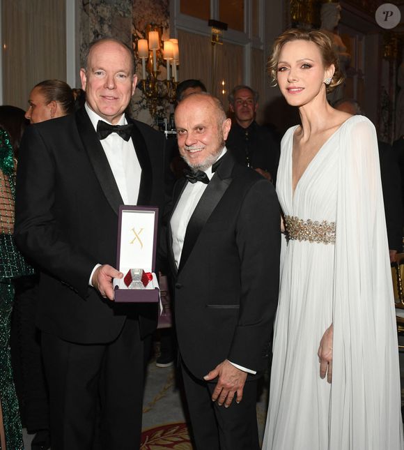 Le prince Albert II de Monaco et la princesse Charlene avec l'un des partenaires de la soirée lors du Bal de Noël à la salle Empire de l'hôtel de Paris à Monaco, le 12 décembre 2025. © Bruno Bebert / Bestimage