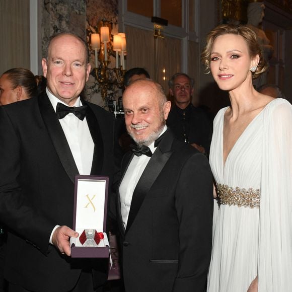 Le prince Albert II de Monaco et la princesse Charlene avec l'un des partenaires de la soirée lors du Bal de Noël à la salle Empire de l'hôtel de Paris à Monaco, le 12 décembre 2025. © Bruno Bebert / Bestimage