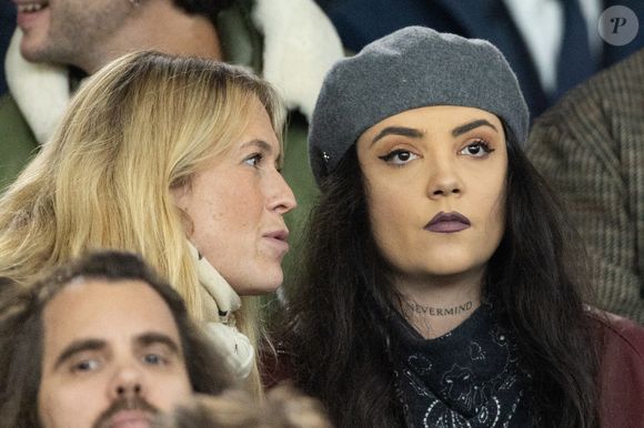 Une douce soirée pour l'artiste qui avait évoqué sa rupture douloureuse avec Gia Martinelli survenue fin 2024 et qu'elle avait mis en musique dans le titre "Tu vas me quitter encore longtemps ?" Hoshi avec une amie dans les tribunes du match de football de qualification pour la coupe du monde 2026 opposant la France à Azerbaïdjan (3-0) au Parc des Princes à Paris, France, le 10 octobre 2025. © Cyril Moreau/Bestimage