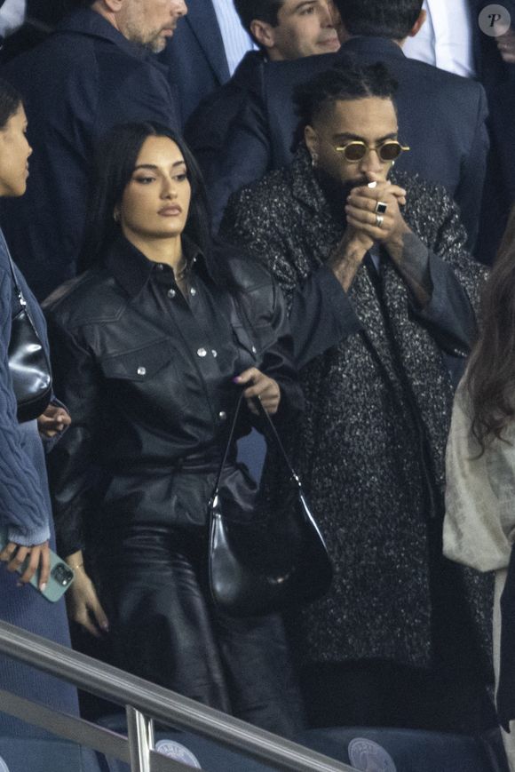 "Certes, cette adresse est petite, seulement 30 mètres carrés mais je l’ai pensée comme un écrin intimiste pour mes créations", avait-elle confié dans les pages du Figaro.

Amina Muaddi, la créatrice de mode qui aurait eu une liaison avec la rappeur ASAP Rocky (qui est le compagnon de Rihanna, actuellement enceinte) et son compagnon Fary dans les tribunes lors du match de Ligue 1 "PSG - OM (2-1)" au Parc des Princes, le 17 avril 2022. © Agence/Bestimage