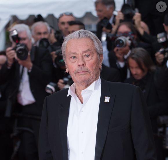 Une façon de montrer que les deux artistes étaient étroitement liés.
Alain Delon (Palme d'Or d'Honneur du 72ème festival de Cannes avec un badge Paris Match d'une ancienne couverture du magazine titrant "Alain Delon, mes deux amours, Rosalie et Anouchka) - Montée des marches du film "A Hidden Life" lors du 72ème Festival International du Film de Cannes. Le 19 mai 2019
©Backgrid UK/ Bestimage