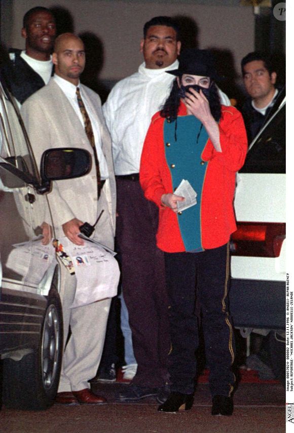 Novembre 1996, Auckland. Michael Jackson masqué, coiffé d’un chapeau, devant l’hôtel Carlton, entouré de ses gardes du corps. © Alpha Agency / Bestimage