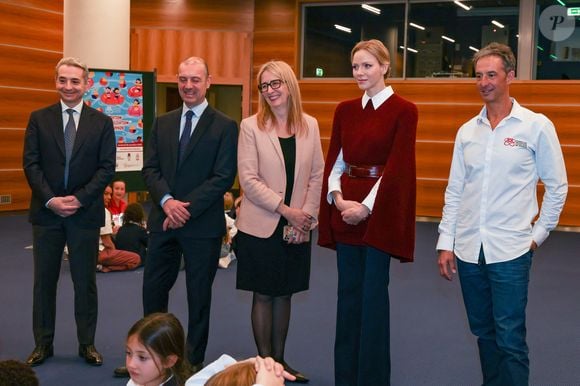 Elle portait notamment la robe/cape Astoria de chez Maxmara en laine et cachemire de couleur framboise 

La princesse Charlène de Monaco au Grimaldi Forum, accompagnée du champion monégasque de descente en apnée, Pierre Frolla, et la nouvelle directrice de sa Fondation Mme Anne Boggio, pour accueillir tous les élèves de Cours Préparatoire (CP) de Monaco (316 enfants) pour une matinée de sensibilisation à la prévention de la noyade à Monaco, le 28 novembre 2025. Claudia Albuquerque/Bestimage