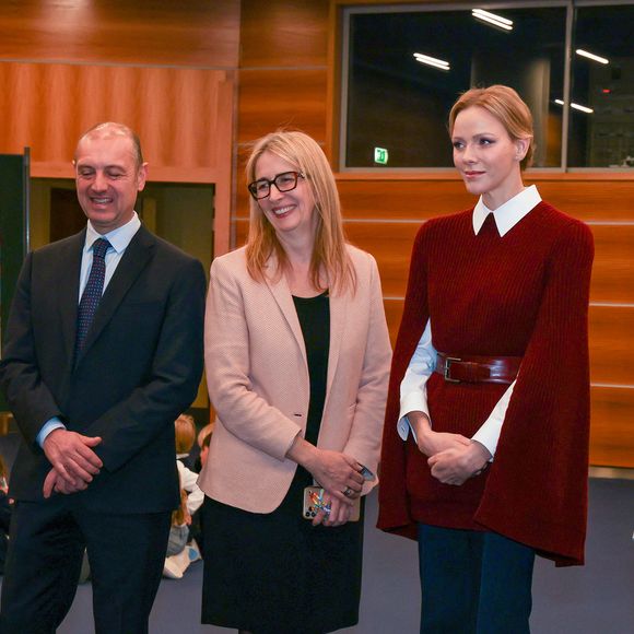Elle portait notamment la robe/cape Astoria de chez Maxmara en laine et cachemire de couleur framboise 

La princesse Charlène de Monaco au Grimaldi Forum, accompagnée du champion monégasque de descente en apnée, Pierre Frolla, et la nouvelle directrice de sa Fondation Mme Anne Boggio, pour accueillir tous les élèves de Cours Préparatoire (CP) de Monaco (316 enfants) pour une matinée de sensibilisation à la prévention de la noyade à Monaco, le 28 novembre 2025. Claudia Albuquerque/Bestimage