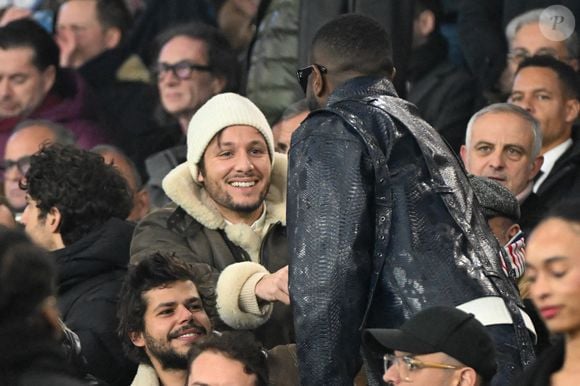 Vianney et Gims dans les tribunes du match de Ligue 1 McDonald's opposant le Paris Saint-Germain (PSG) à Lyon (3-1) au Parc des Princes à Paris le 15 décembre 2024.