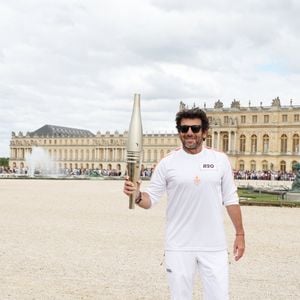 Le chanteur et acteur Patrick Bruel porteur de la flamme olympique des Jeux Olympiques de Paris 2024 (JO) au château de Versailles dans les Yvelines, France, le 23 juillet 2024. © Dominique Jacovides/Bestimage