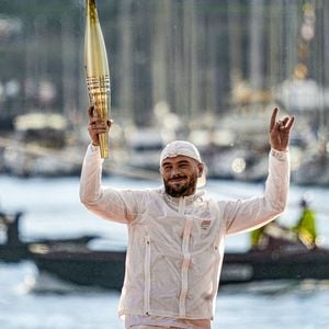 Dans ce pop-up store événementiel, les inconditionnels de l'artiste pourront faire le plein de pépites. Sur les étagères ? Le tout dernier album du phénomène marseillais pour vibrer sur ses nouveaux hits, mais aussi les toutes dernières nouveautés de sa célèbre marque de vêtements, D'Or et de Platine. De quoi refaire sa garde-robe aux couleurs du rappeur juste avant l'été.
Le rappeur Jul embrase le chaudront olympique lors de la cérémonie d'arrivée de la flamme olympique au Vieux-Port de Marseille, France, le 8 mai 2024, avant les Jeux olympiques et paralympiques de Paris 2024. © Sandrine Thesillat/Panoramic/Bestimage