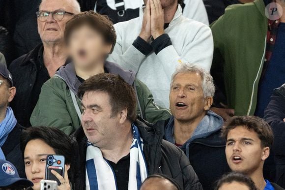 Nagui et son fils Adrien Fam - Célébrités dans les tribunes du match de Ligue des Champions entre le PSG contre le Bayern de Munich (1-2) au Parc des Princes à Paris le 4 novembre 2025. © Cyril Moreau/Bestimage Celebrities in the stands at the Champions League match between PSG and Bayern Munich (1-2) at the Parc des Princes in Paris on November 4, 2025.