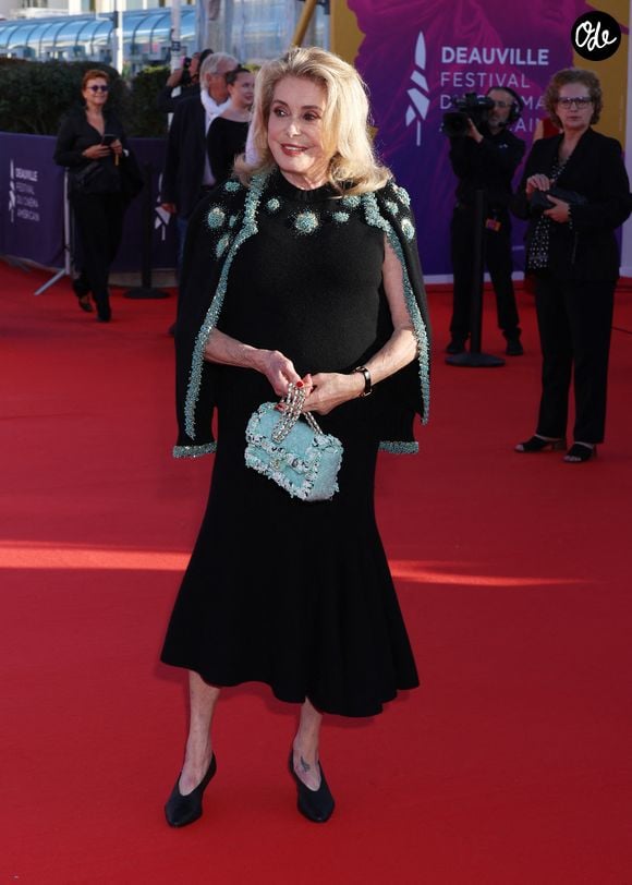 Invitée d’honneur, Catherine Deneuve s'est présentée sur le tapis rouge vêtue d’une tenue Chanel des plus chics. Elle portait alors une jupe évasée s’arrêtant à mi-mollet ainsi qu’un haut en maille composé de perles bleu ciel et dorées au col. Une veste assortie était délicatement posée sur ses épaules.

Catherine Deneuve - Arrivées à la cérémonie de clôture de la 52ème édition du Festival du Cinéma Américain de Deauville le 12 septembre 2026. © Denis Guignebourg / Bestimage