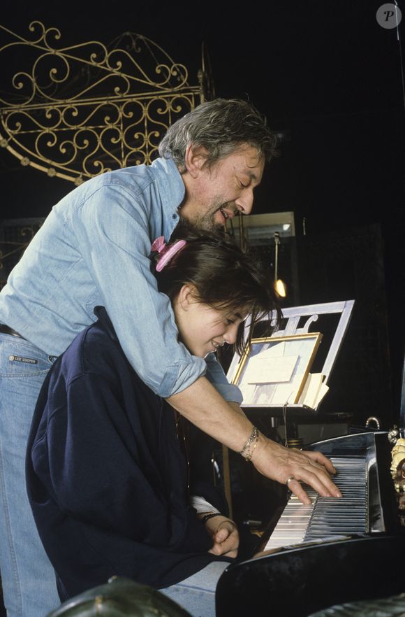 En France, à Paris, Serge Gainsbourg chez lui avec sa fille Charlotte dans son hôtel particulier de la rue de Verneuil, posant au milieu de son bric-à-brac où il entasse des objets hétéroclites en mai 1985.  © Michel Marizy via Bestimage