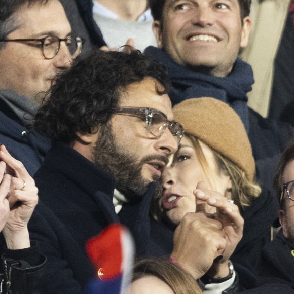 Maxim Nucci (Yodelice) et sa compagne Isabelle Ithurburu dans les tribunes lors du match de rugby du Tournoi des 6 Nations opposant la France à l'Angleterre au stade de France, à Saint-Denis, Seine Saint-Denis, France, le 19 mars 2022. © Cyril Moreau/Bestimage