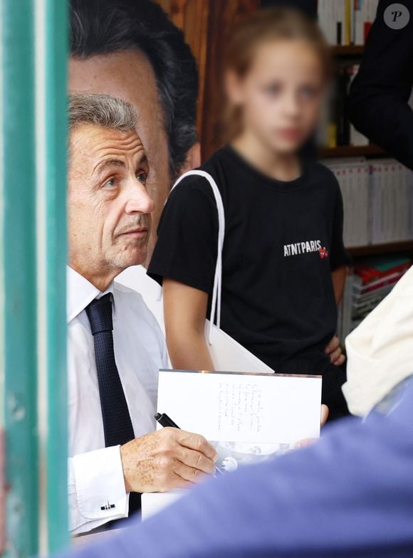 L'ancien président de la République française Nicolas Sarkozy dédicace son livre "Le temps des Combats" sous l'oeil attentif de sa fille Giulia à la Librairie du Marché à Deauville, France, le 1er septembre 2023. © Denis Guignebourg/Bestimage