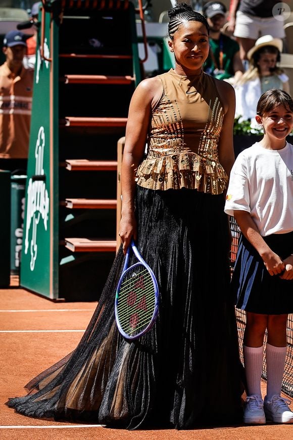 Mardi dernier, lors de son premier match, elle avait déjà marqué les esprits en entrant sur le court avec une longue robe noire structurée, avant de dévoiler sa tenue de match beige et or.

Théma - La joueuse de tennis Naomi Osaka et ses tenues improbables - Naomi OSAKA du Japon lors de la troisième journée de Roland-Garros 2026, Roland-Garros 2026, tournoi de tennis du Grand Chelem au stade Roland-Garros le 26 mai 2026 à Paris, France. Matthieu Mirville/ZUMA Press Wire/Bestimage