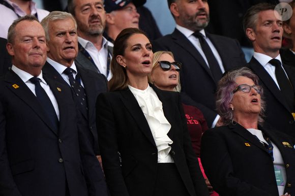 Kate Middleton portait un tailleur noir Alexander McQueen et une chemise à jabot.

La Princesse de Galles (au centre) dans les tribunes pendant l'hymne national lors du match de poule A de la Coupe du monde de rugby féminin 2025 à l'American Express Stadium, Brighton. Samedi 6 septembre 2025. Photo by Ben Whitley/PA Wire/ABACAPRESS.COM