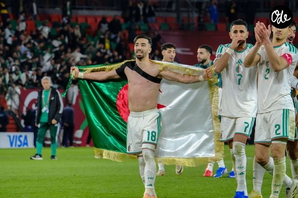 Algerian players celebrate AFCON Round of 16 victory with national flag RABAT, MOROCCO - JANUARY 06: Houssem Aouar 18 draped in the Algerian flag celebrates with teammates Riyad Mahrez 7 and Aissa Mandi 2 as they thank the supporters following their victory over DR Congo in the AFCON 2025 Round of 16 at Stade Moulay El Hassan on January 06, 2026