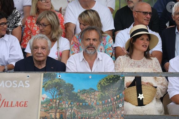 Semi-exclusif - Michel Sardou, Romain Sardou et sa compagne Kym Thiriot enceinte - Michel Sardou rend hommage à son père en famille lors du premier trophée de pétanque "Fernand Sardou" à Bormes-les-Mimosas le 29 mai 2026. Le célèbre chanteur est venu en famille avec sa femme, son fils Romain avec son fils de deux ans et demi et de sa compagne enceinte de son deuxième enfant.
La première édition du Trophée Fernand Sardou est organisée du 29 au 31 mai au coeur du village de Bormes les Mimosas. Une initiative portée par Michel et son fils Romain, pour rendre hommage à leur illustre parent Fernand Sardou au travers d'un tournoi de pétanque.
En lien avec la municipalité et l'Amicale Bouliste Borméenne (ABB), un premier Trophée Fernand Sardou sera organisé avec deux grands temps forts : Le vendredi, dès 18h, un tournoi d'exhibition sera proposé et verra s'affronter 16 triplettes. Puis un concours fédéral à pétanque sera organisé le weekend et ouvert à tous les amateurs. 128 équipes seront réparties sur les sites les plus emblématiques du village, à savoir au boulodrome de la place Saint-François, mais aussi au parc Cigalou, sur le site du château et à l'ancien stade. © Franz Chavaroche/Bestimage