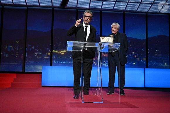 Le réalisateur brésilien Kleber Mendonca Filho reçoit le prix du meilleur réalisateur et est accompagné par le réalisateur français Claude Lelouch pour le film "O Agente Secreto" (L'agent secret) du réalisateur français Claude Lelouch lors de la cérémonie de clôture de la 78e édition du Festival de Cannes à Cannes, dans le sud de la France, le 24 mai 2025.