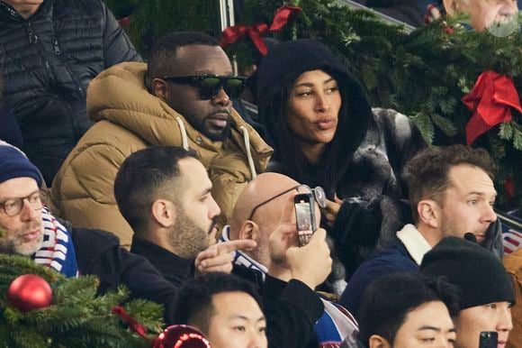 Gims et sa femme DemDem dans les tribunes du match de Ligue 1 McDonald's opposant le Paris Saint-Germain (PSG) à Lyon (3-1) au Parc des Princes à Paris le 15 décembre 2024.