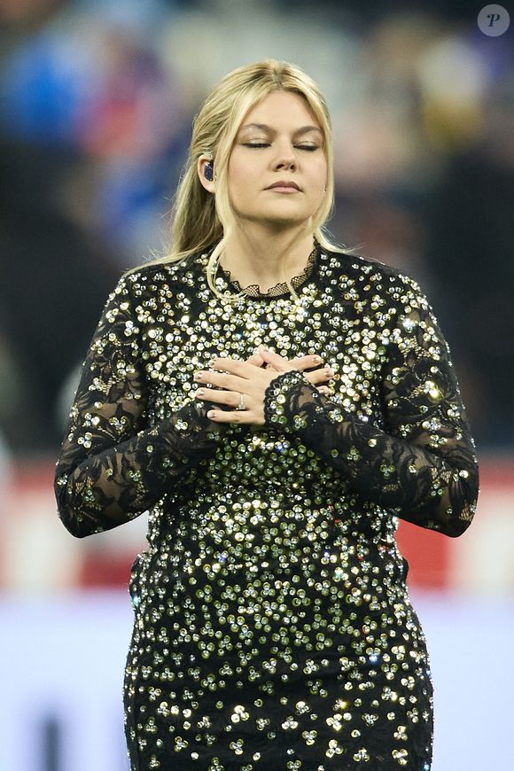 La chanteuse Louane (Louane Emera), représentante de la France au concours de l'Eurovision, interprète pour la première fois son titre Maman, en hommage à sa mère décédée lorsqu'elle avait 17 ans, devant les 80 000 spectateurs, suspendue sur une plateforme, plusieurs mètres au-dessus de la pelouse et des musiciens, du Stade de France à la mi-temps du match du Tournoi des Six Nations opposant la France à l'Écosse, à Saint-Denis, Seine Saint-Denis, France, le 15 mars 2025. © Cyril Moreau/Bestimage