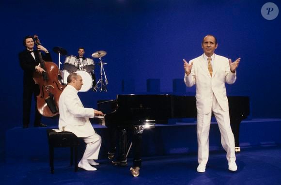 À Paris, en 1989, Claude Bolling, pianiste, jouant du piano et Guy Marchand, chantant, devant l'orchestre.