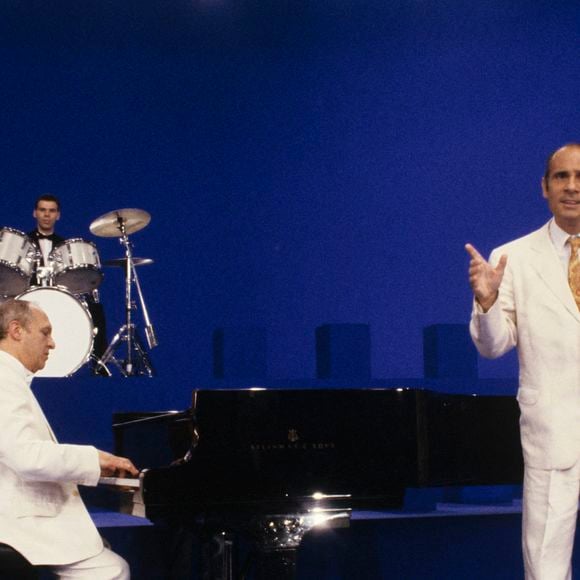 À Paris, en 1989, Claude Bolling, pianiste, jouant du piano et Guy Marchand, chantant, devant l'orchestre.