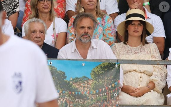Semi-exclusif - Michel Sardou, Romain Sardou et sa compagne Kym Thiriot enceinte - Michel Sardou rend hommage à son père en famille lors du premier trophée de pétanque "Fernand Sardou" à Bormes-les-Mimosas le 29 mai 2026. Le célèbre chanteur est venu en famille avec sa femme, son fils Romain avec son fils de deux ans et demi et de sa compagne enceinte de son deuxième enfant.
La première édition du Trophée Fernand Sardou est organisée du 29 au 31 mai au coeur du village de Bormes les Mimosas. Une initiative portée par Michel et son fils Romain, pour rendre hommage à leur illustre parent Fernand Sardou au travers d'un tournoi de pétanque.
En lien avec la municipalité et l'Amicale Bouliste Borméenne (ABB), un premier Trophée Fernand Sardou sera organisé avec deux grands temps forts : Le vendredi, dès 18h, un tournoi d'exhibition sera proposé et verra s'affronter 16 triplettes. Puis un concours fédéral à pétanque sera organisé le weekend et ouvert à tous les amateurs. 128 équipes seront réparties sur les sites les plus emblématiques du village, à savoir au boulodrome de la place Saint-François, mais aussi au parc Cigalou, sur le site du château et à l'ancien stade. © Franz Chavaroche/Bestimage